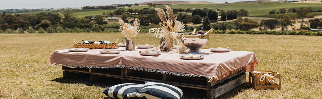 A picnic table sits on lush lawns overlooking vineyards.